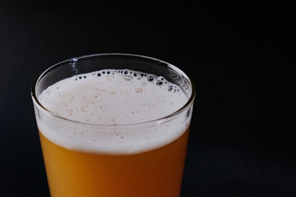 A detailed close-up of a frothy beer glass against a black background, highlighting the foam and bubbles.
